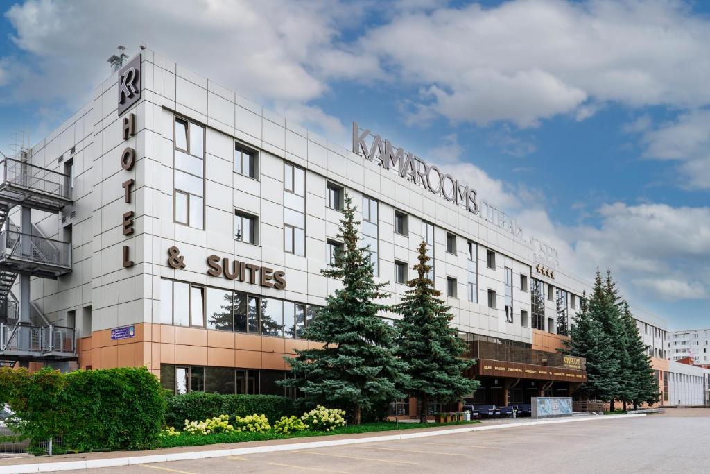a large white building with trees in front of it at Kamarooms Business Hotel & Spa in Naberezhnyye Chelny