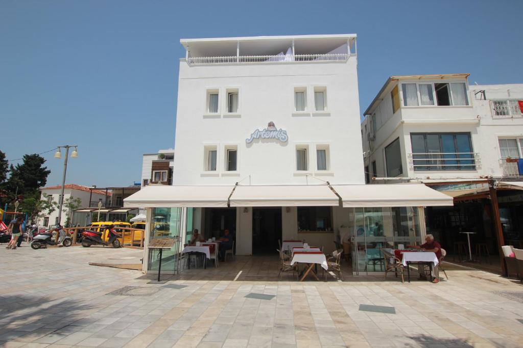 a white building with tables in front of it at Artemis Hotel in Bodrum City