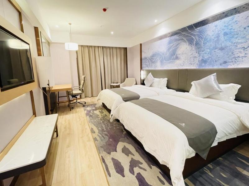 duży pokój hotelowy z dwoma łóżkami i telewizorem w obiekcie GreenTree Eastern Guangxi Baise Wuzhong Sports Center High-Speed Railway Station 