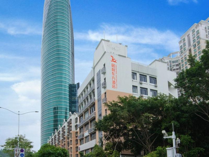 dois altos edifícios de vidro numa cidade com árvores em GreenTree Eastern Hotel Shenzhen Futian Civic Center Jingtan Subway Station em Shenzhen