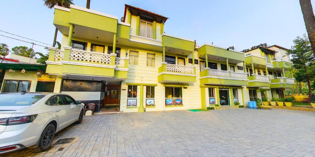 卜山Hotel Vishram的一栋黄色建筑，前面停着一辆汽车