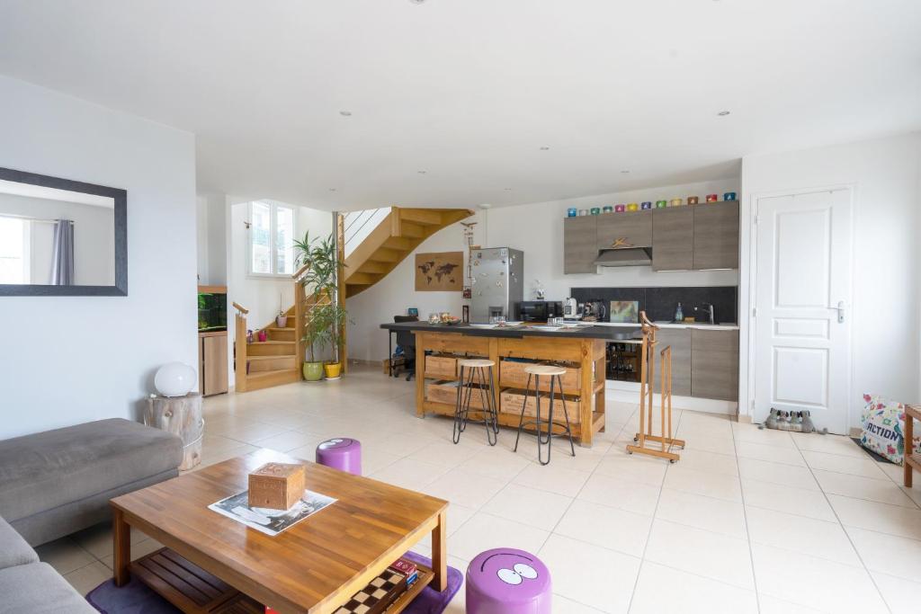ein Wohnzimmer und eine Küche mit einem Sofa und einem Tisch in der Unterkunft La Guinebaudière - Maison avec terrasse in Naveil