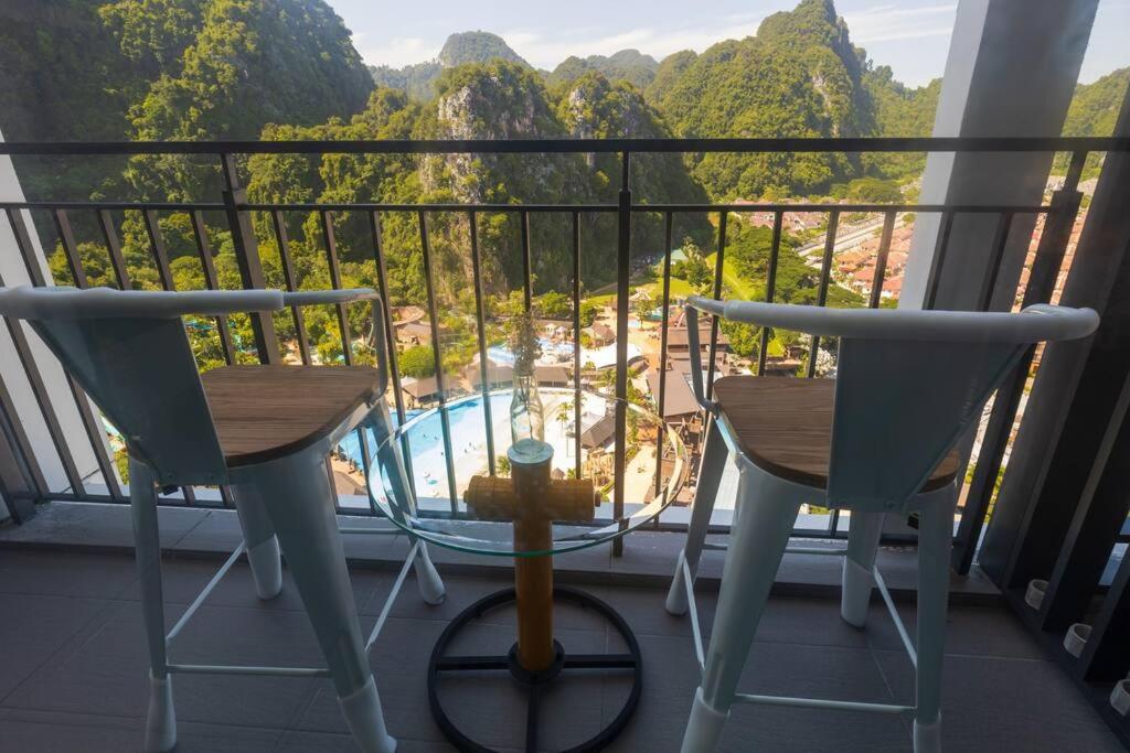 een balkon met 2 stoelen en uitzicht op een zwembad bij Happy Home Sunway Onsen hi-floor theme park view Lost World of Tambun in Tambun