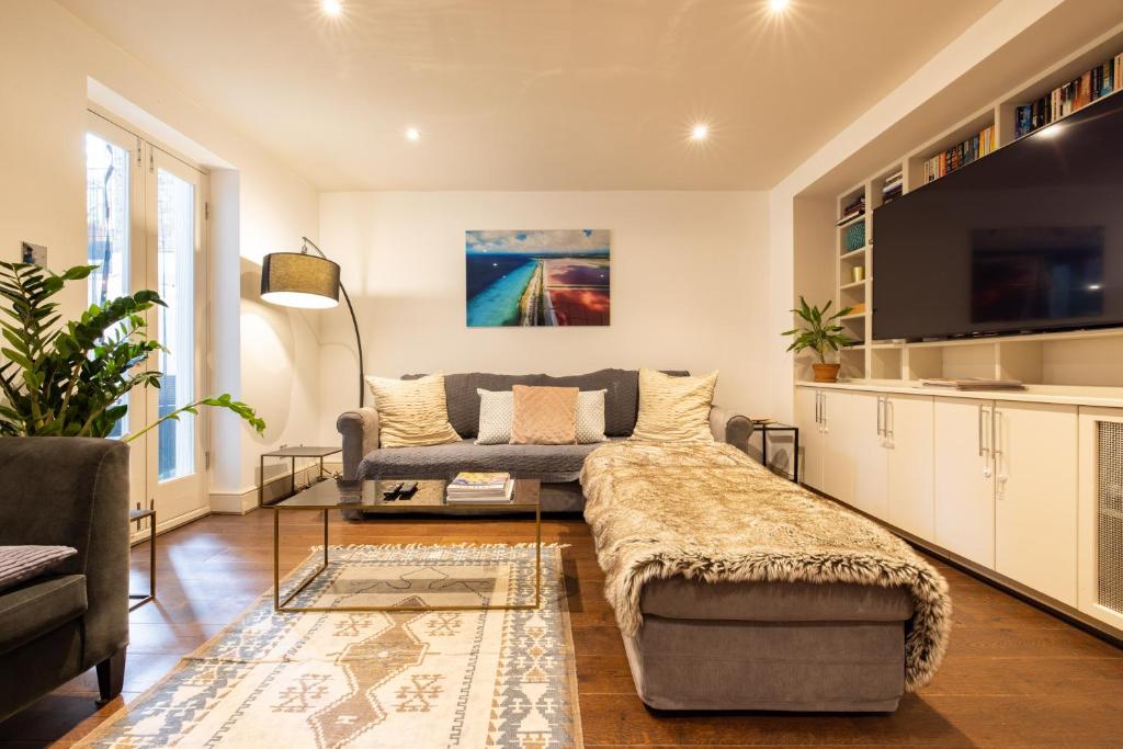 uma sala de estar com um sofá e uma televisão em Niru Experience Hidden Gem in Chelsea em Londres