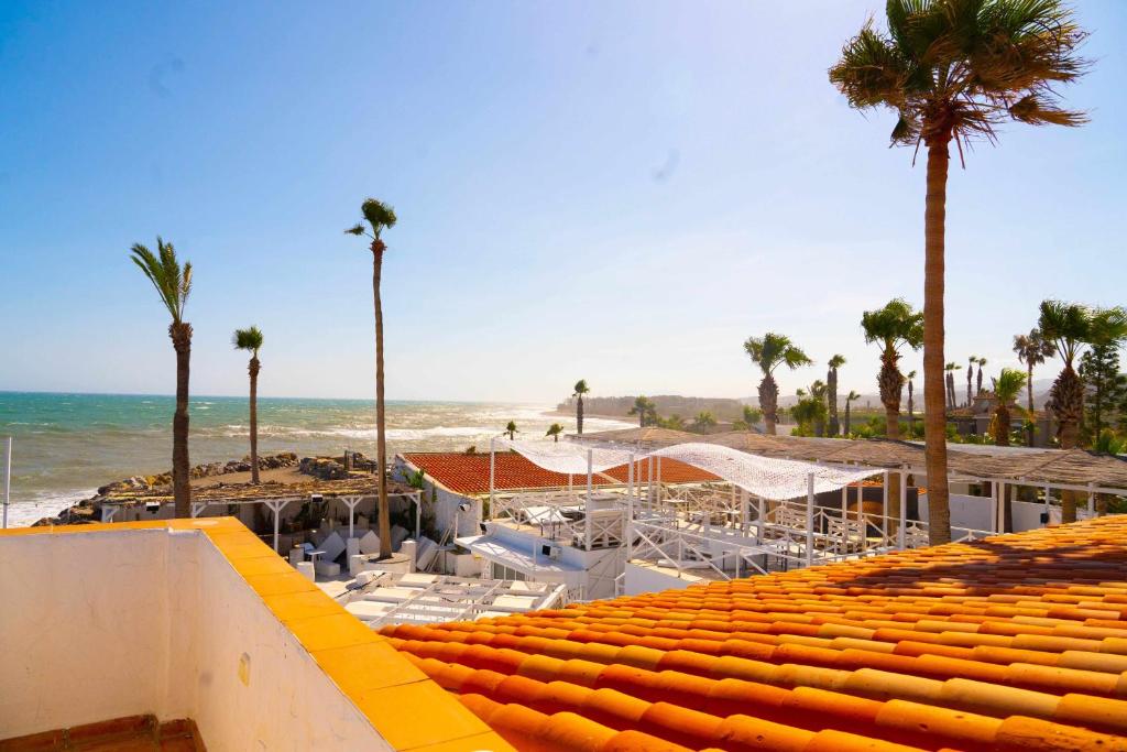 Hostal Paraiso del Mar في توري ذيل مار: اطلالة على شاطئ فيه نخل ومبنى