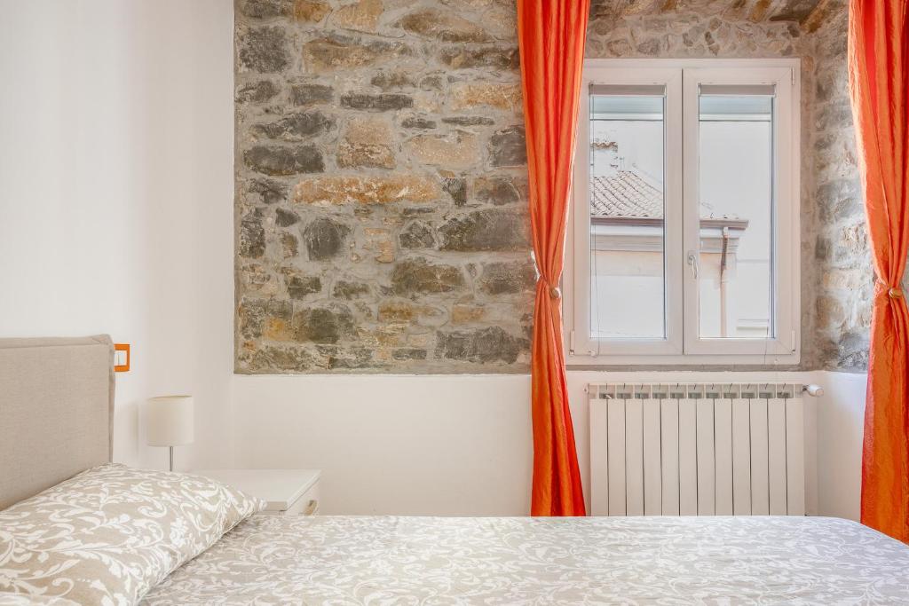 - une chambre avec un lit et une fenêtre avec des rideaux orange dans l'établissement CIVICO UNO, à Trieste