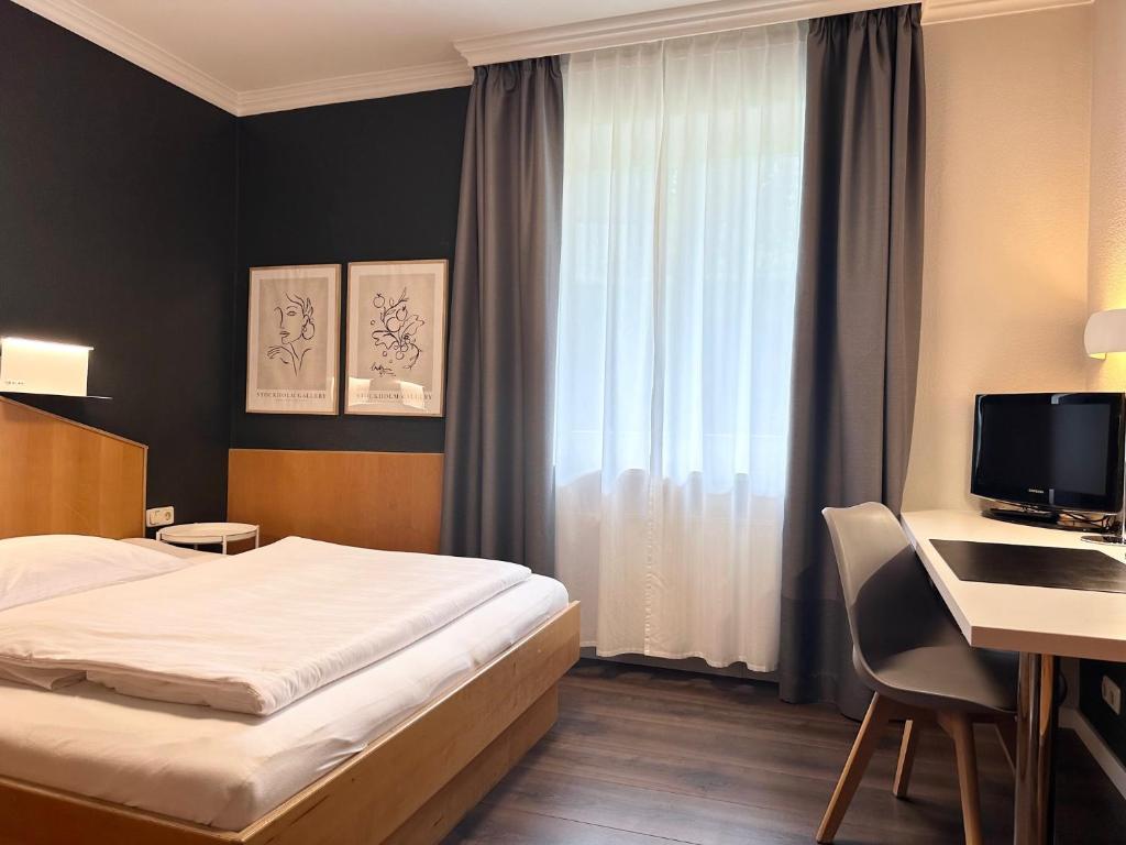 Habitación de hotel con cama y escritorio con ordenador en Hotel Villa Solln en Múnich