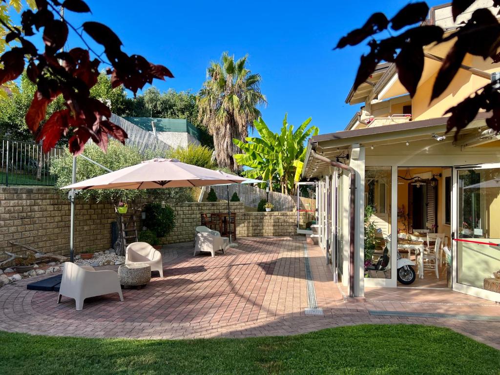 a patio with an umbrella and chairs and tables at Peperosa in collina B&B in Pescara