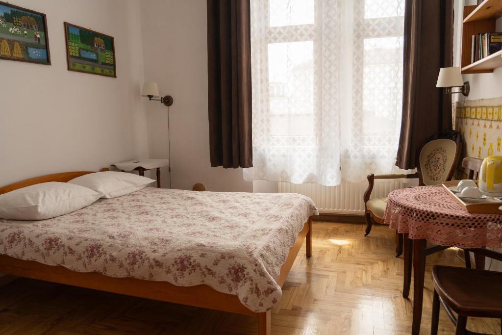 a bedroom with a bed and a table and a window at Kolory Guest House in Kraków