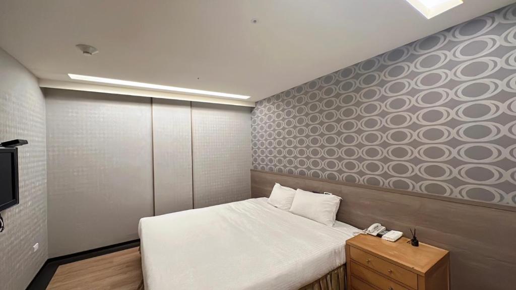1 dormitorio pequeño con 1 cama y TV en Crystal City Hotel, en Zhongli