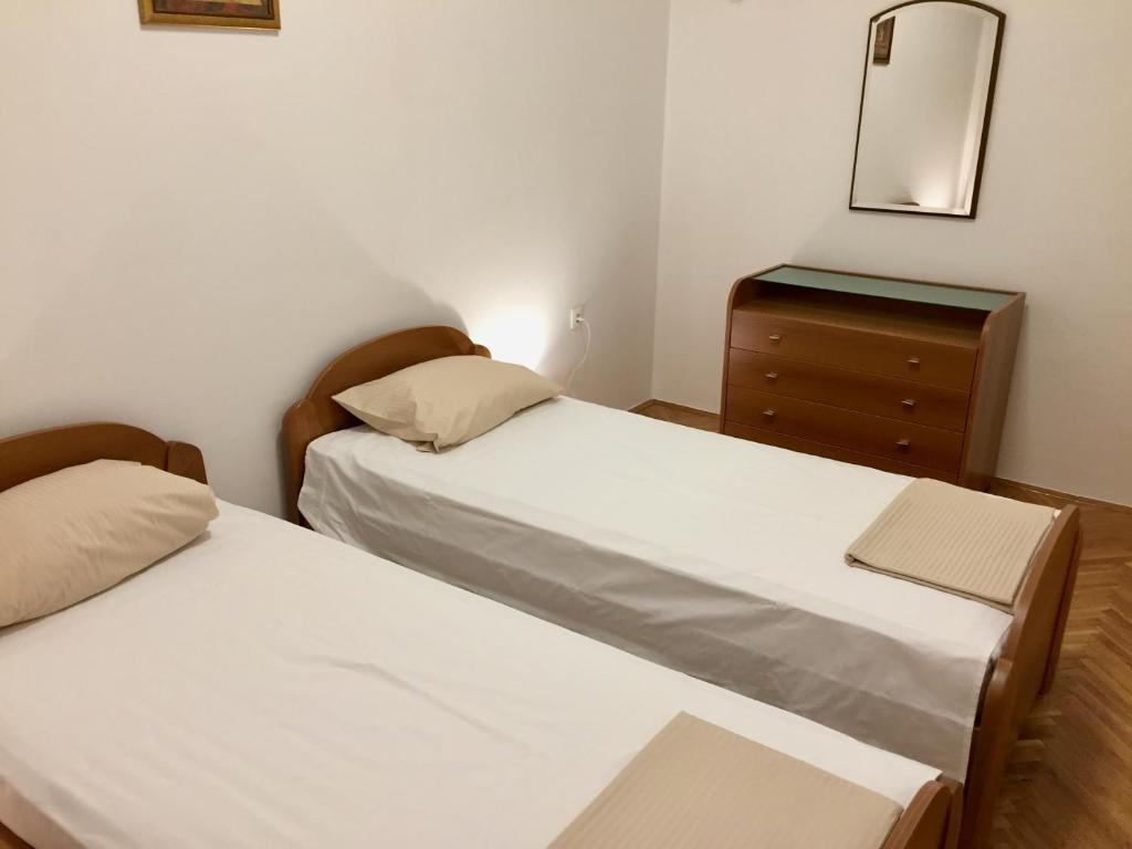 2 letti in una camera con cassettiera e specchio di Guest House Gaj Sarajevo a Sarajevo