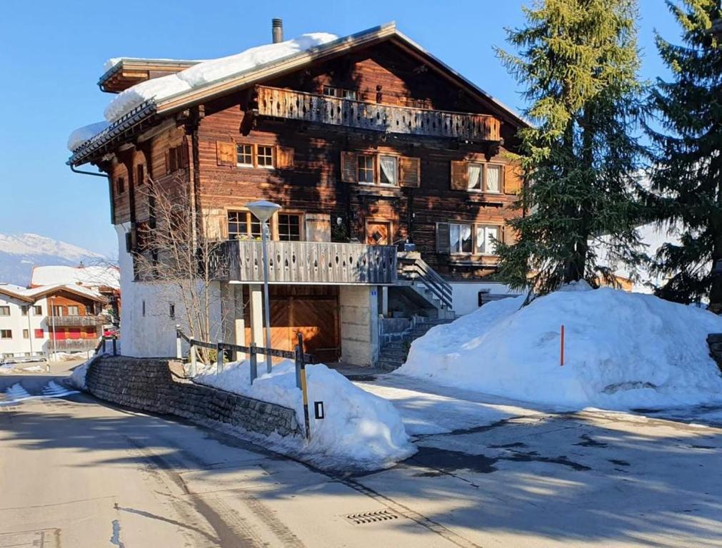 a large wooden house with snow around it at Haushälfte Ober Misanenga in Obersaxen