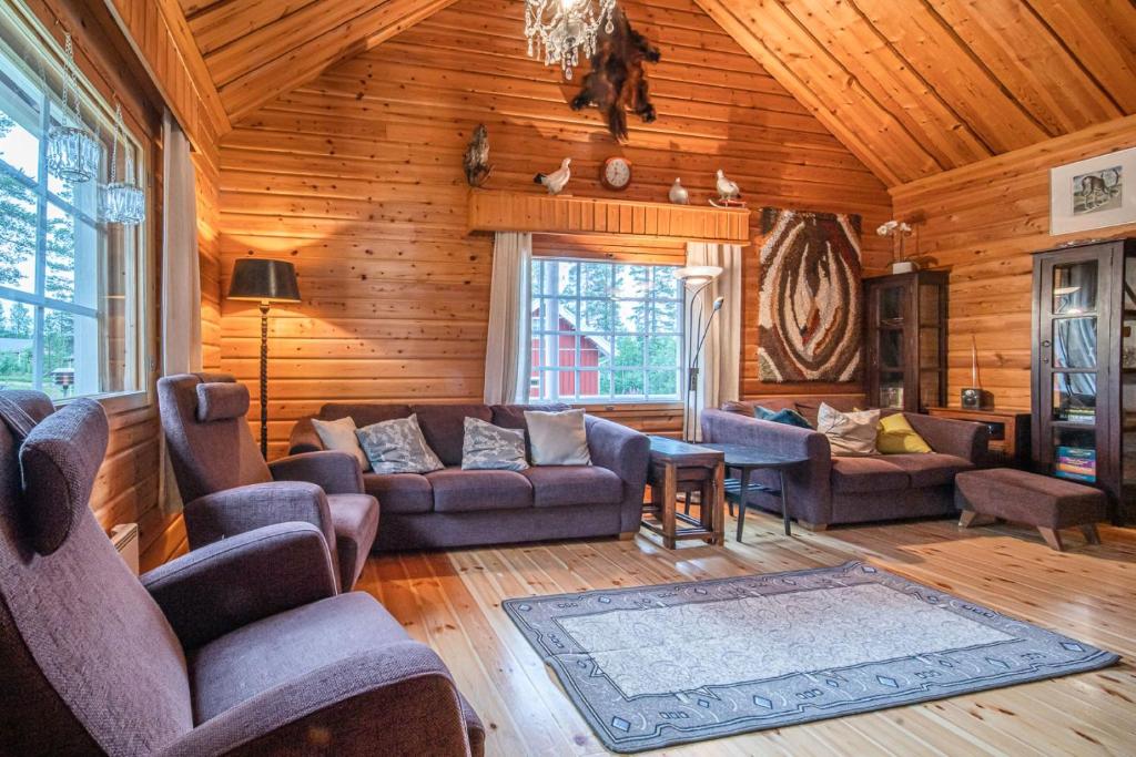 una sala de estar con sofás y sillas en una cabaña de madera en Immelkolo en Levi