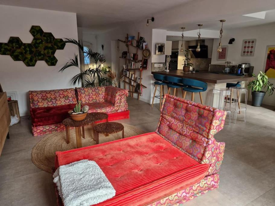 a living room with two red couches and a kitchen at jolie maison à 10 mn à pied du centre d'Aix-en-Provence in Aix-en-Provence
