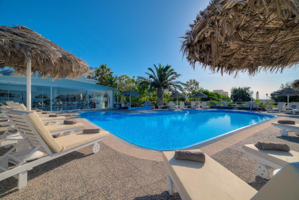 a large swimming pool with lounge chairs and umbrellas at Pantheon Hotel in Perivolos