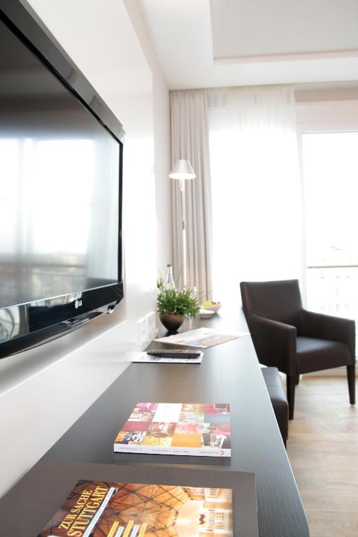 a living room with a television and a table at Parkhotel Stuttgart Messe-Airport in Leinfelden-Echterdingen