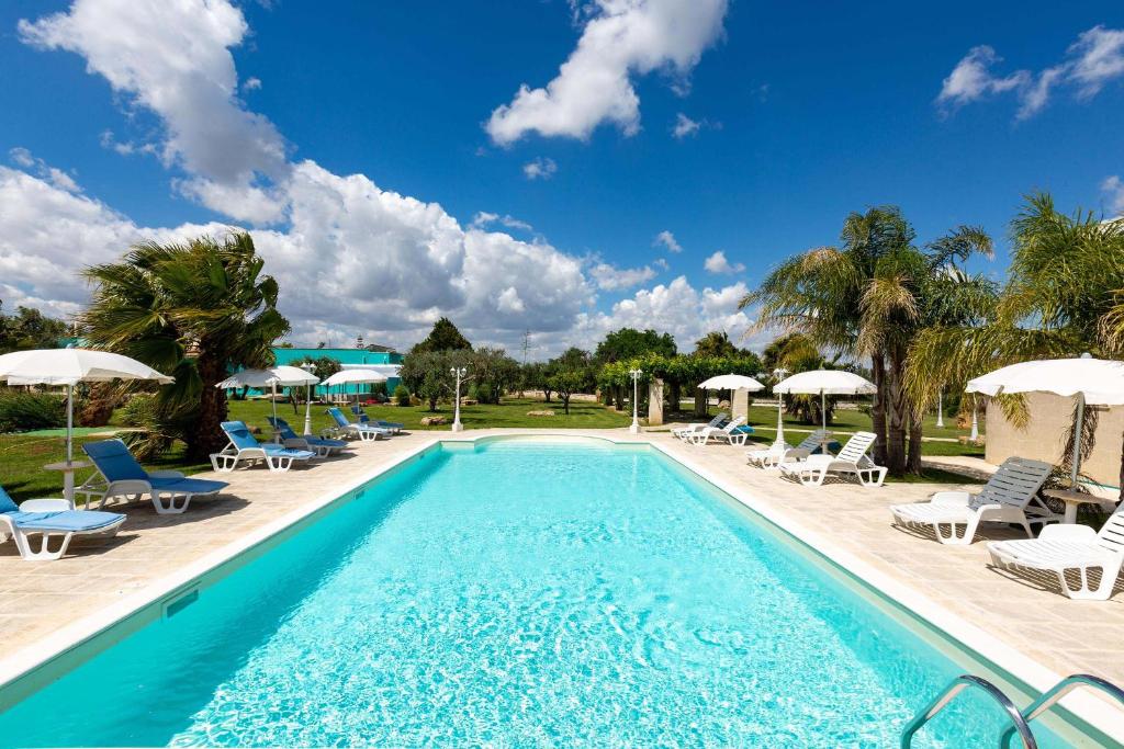 a swimming pool with chairs and umbrellas at Tenuta Donna Caterina by BarbarHouse in Mesagne