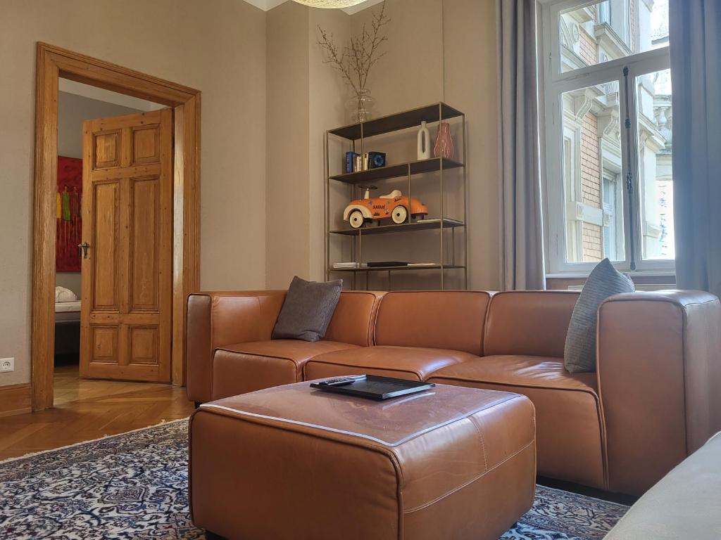 een woonkamer met een bruine bank en een tafel bij Am Thalia Designe Apartment in Baden-Baden