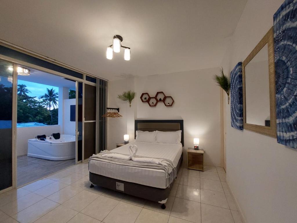 a bedroom with a bed and a bathroom with a tub at Bonsai Jacuzzi Suites in Panglao Island