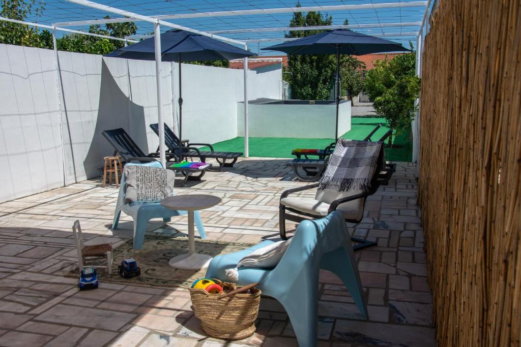 eine Terrasse mit Stühlen, einem Tisch und einem Sonnenschirm in der Unterkunft Casa dos Marianinhos in Elvas