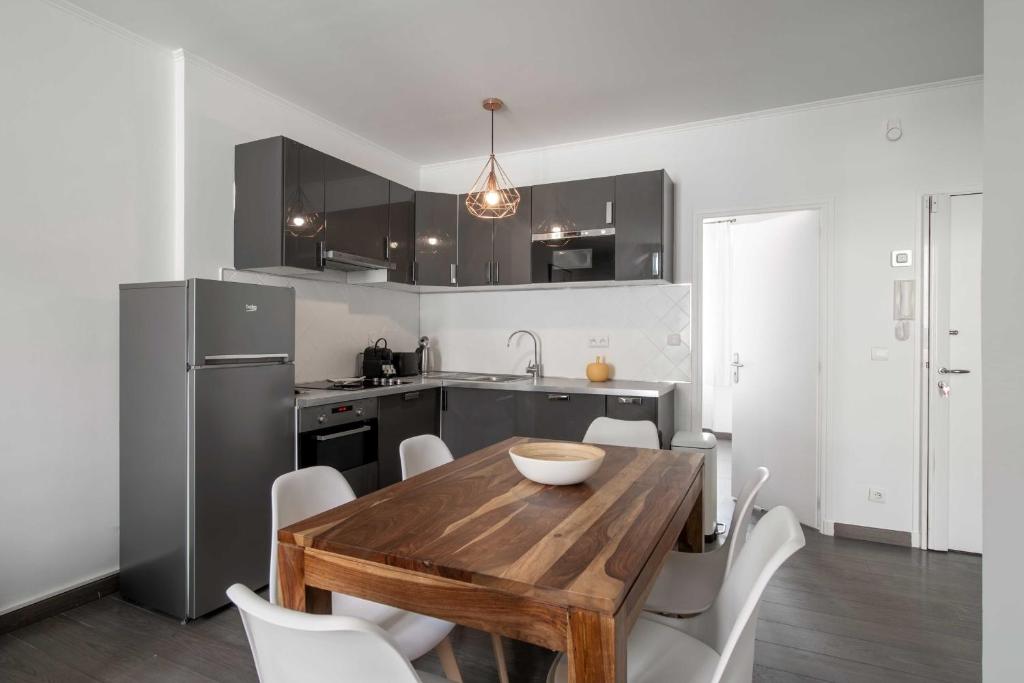 - une cuisine avec une table en bois et des chaises blanches dans l'établissement Bright beautiful apartment - city center Cannes, à Cannes