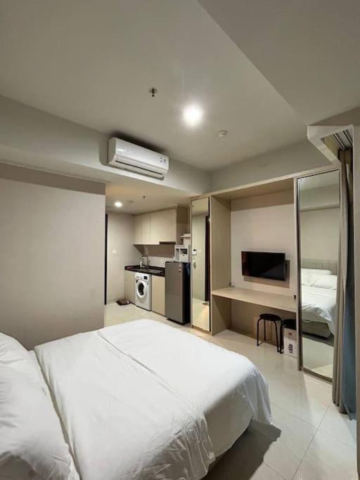 1 Schlafzimmer mit einem großen weißen Bett und einer Küche in der Unterkunft Green Sedayu Apartment - Studio By PSG Grup in Jakarta