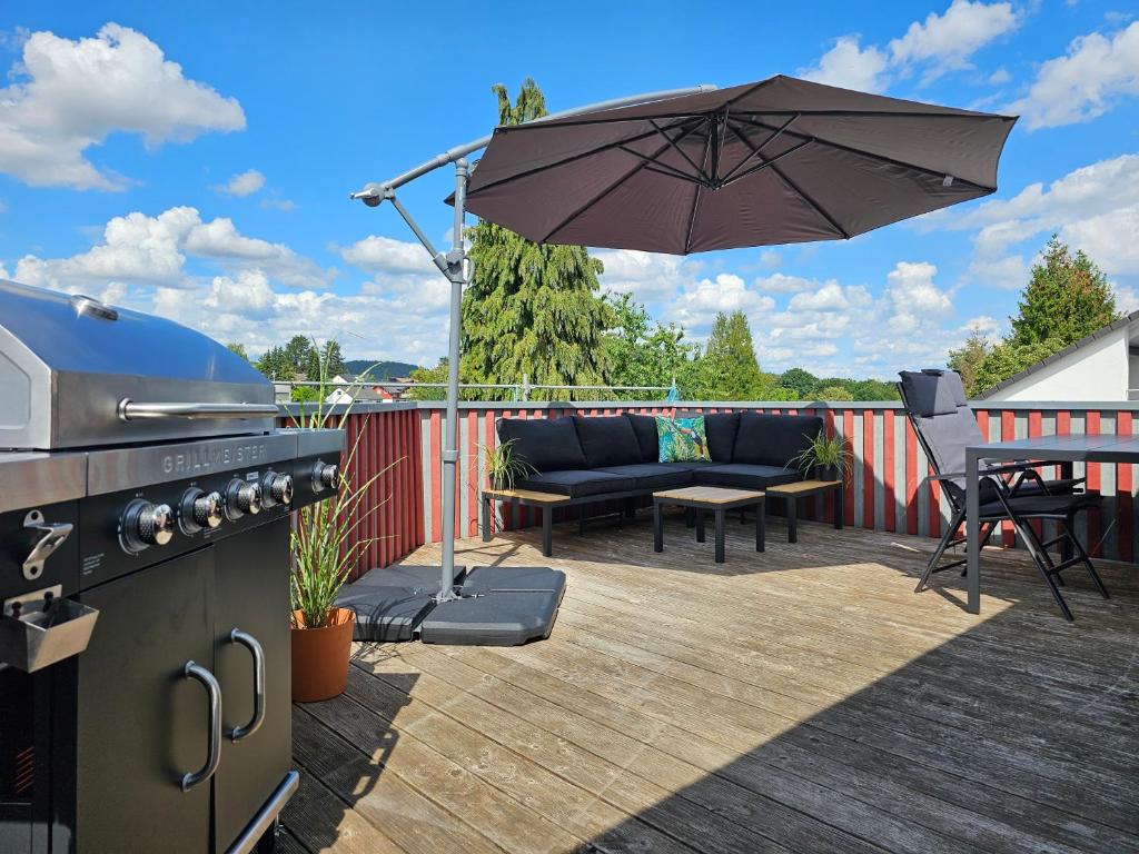 a patio with a grill and an umbrella on a deck at Tucan - Rooftop Terrace with View, BBQ, PS4+Stream in Marburg an der Lahn