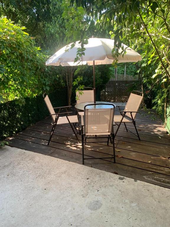 une table, des chaises et un parasol sur une terrasse dans l'établissement Le studio des Myrtes, à Nîmes