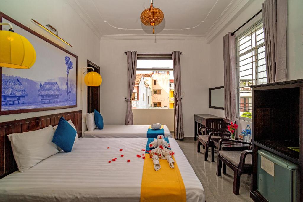 a bedroom with two beds with a baby sitting on the bed at Hoi An Viet House Homestay in Hoi An