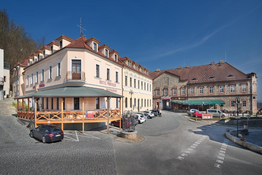 a building on a street with cars parked in a parking lot at Hotel Podhrad in Hluboká nad Vltavou