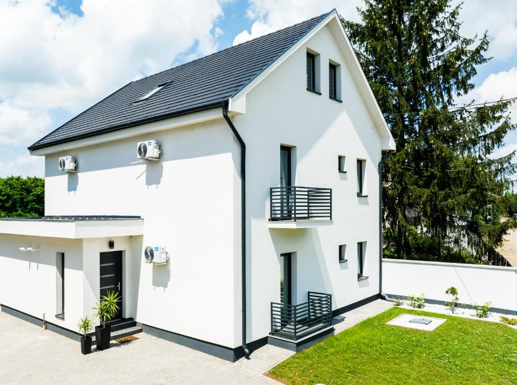 Biały dom z czarnym dachem w obiekcie Kriszta Deluxe Vendégház w mieście Újfehértó