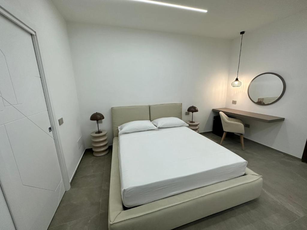 Schlafzimmer mit einem Bett, einem Schreibtisch und einem Spiegel in der Unterkunft Alma Rooms in Lampedusa