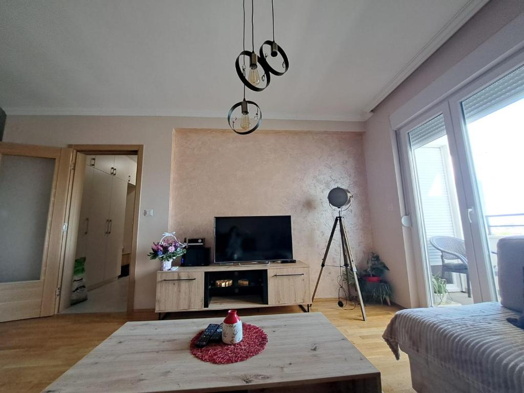 - un salon avec une télévision et une table dans l'établissement VUCETIC Apartment- Podgorica, à Podgorica