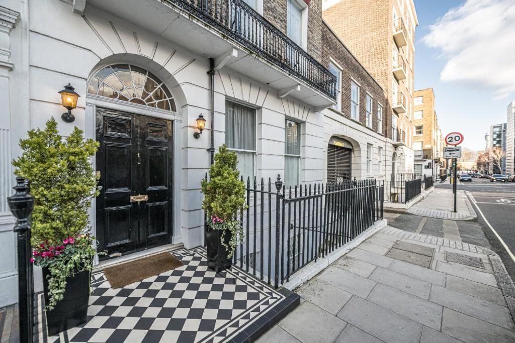 a house with a black door on a checkered sidewalk at Luxury 2 Bedroom Marylebone Apartment in London