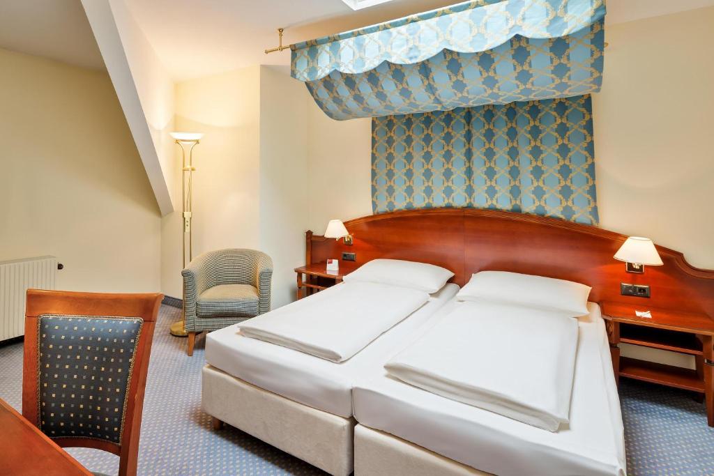 um quarto com uma cama, uma secretária e uma cadeira em Austria Trend Hotel Schloss Wilhelminenberg Wien em Viena
