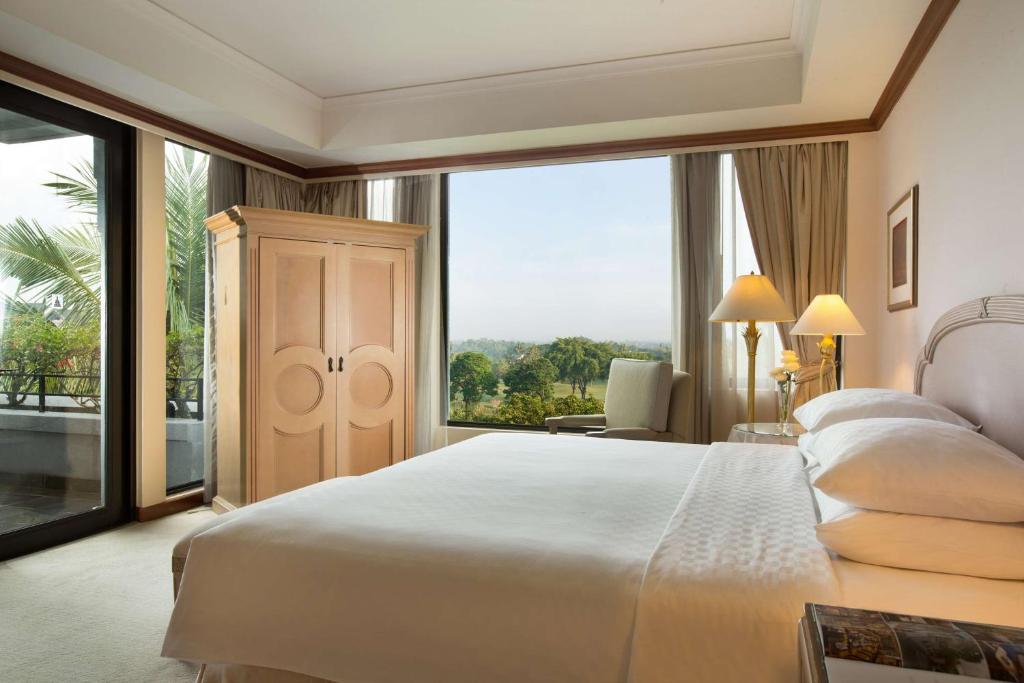a bedroom with a large bed and a large window at Hyatt Regency Yogyakarta in Yogyakarta