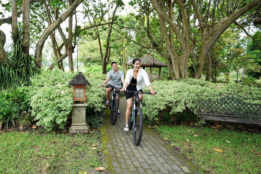 a man and a woman riding bikes in a park at Hyatt Regency Yogyakarta in Yogyakarta