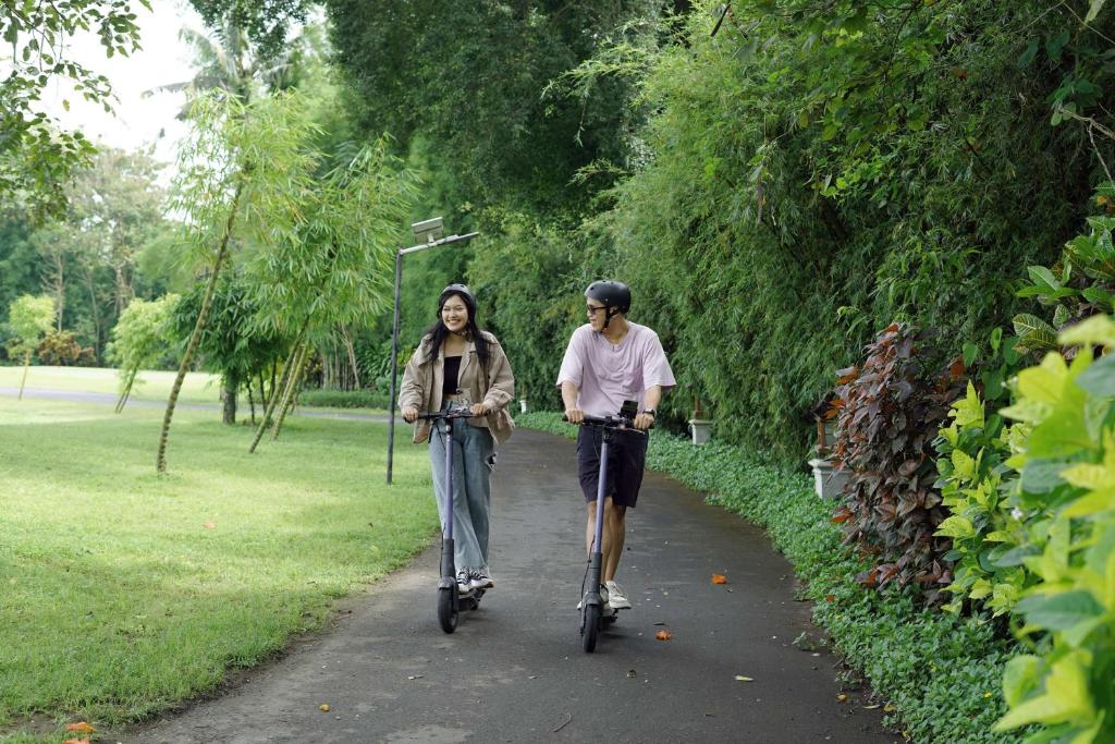 two people riding bikes down a path in a park at Hyatt Regency Yogyakarta in Yogyakarta