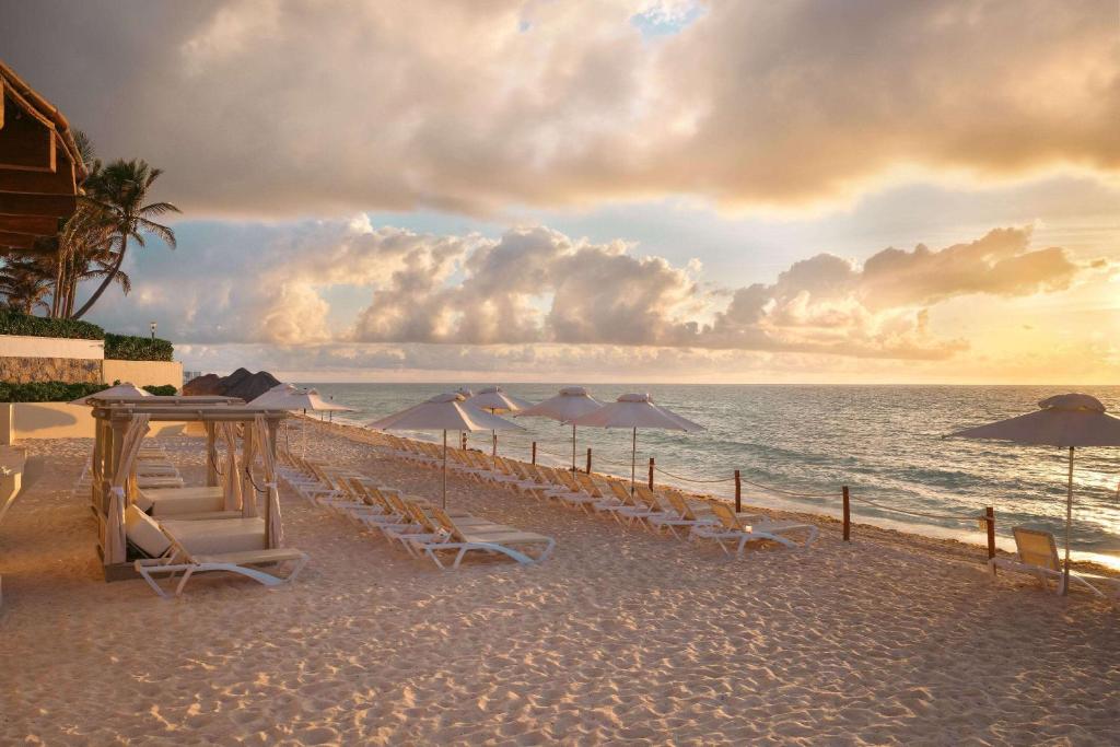 a beach with chairs and umbrellas and the ocean at Wyndham Grand Cancun All Inclusive Resort & Villas in Cancún