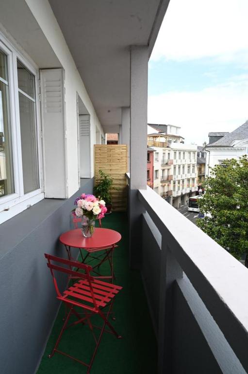a red table with a vase of flowers on a balcony at Grand appartement cosy-Hyper Centre-Place Verdun in Tarbes