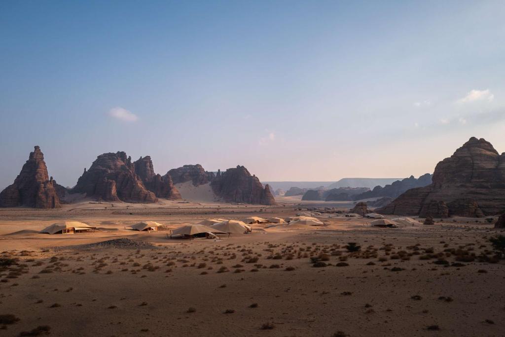 a desert with tents and mountains in the background at Banyan Tree AlUla in AlUla