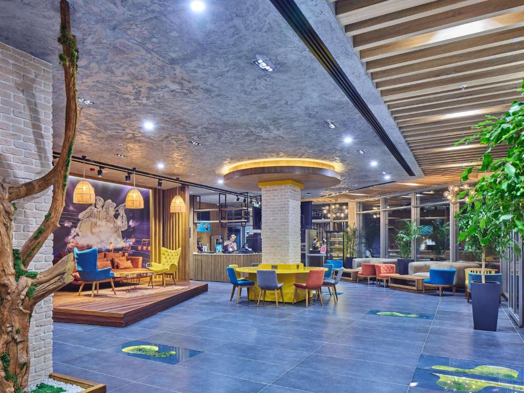 a lobby with colorful chairs and tables in a building at Ibis Istanbul Airport in Istanbul