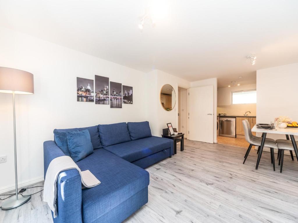 uma sala de estar com um sofá azul e uma mesa em Pass the Keys Fresh and Stylish Central Flat With Parking and Garden em Londres