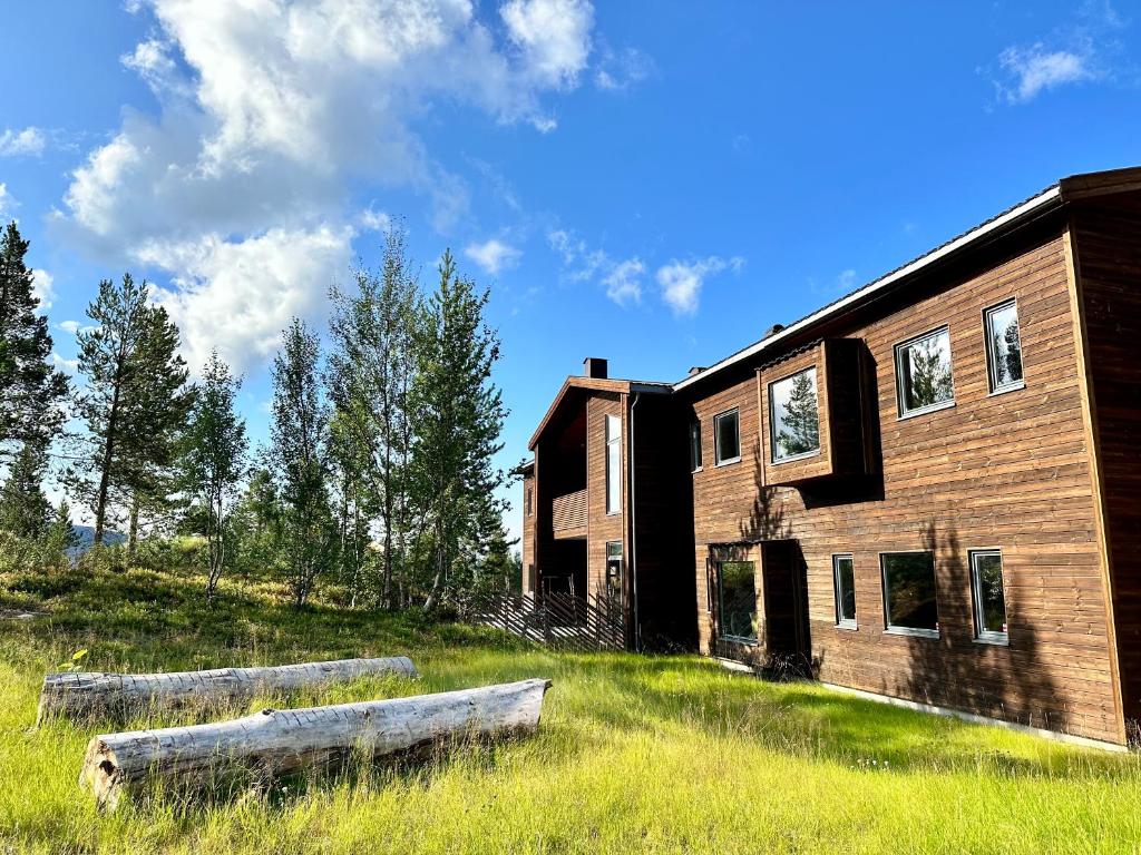 a building with two logs in the grass next to it at Bjørnfjell Mountain Lodge in Alta