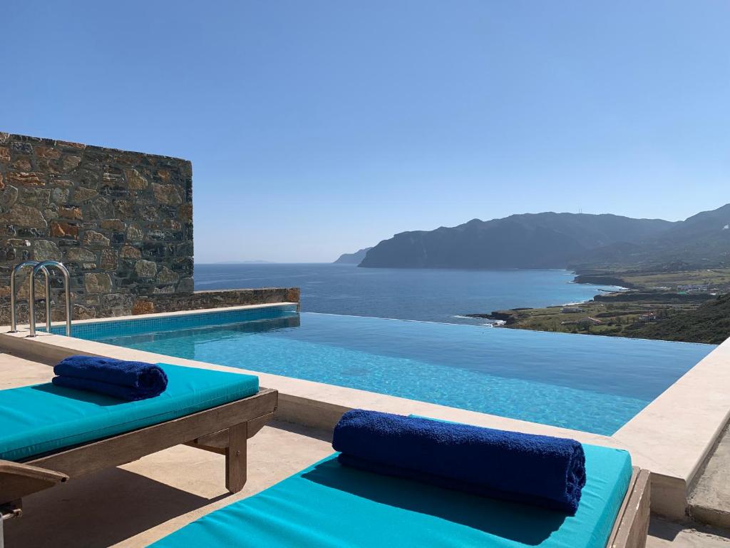 a swimming pool with two blue cushions next to at Petra Nova Villas in Mochlos