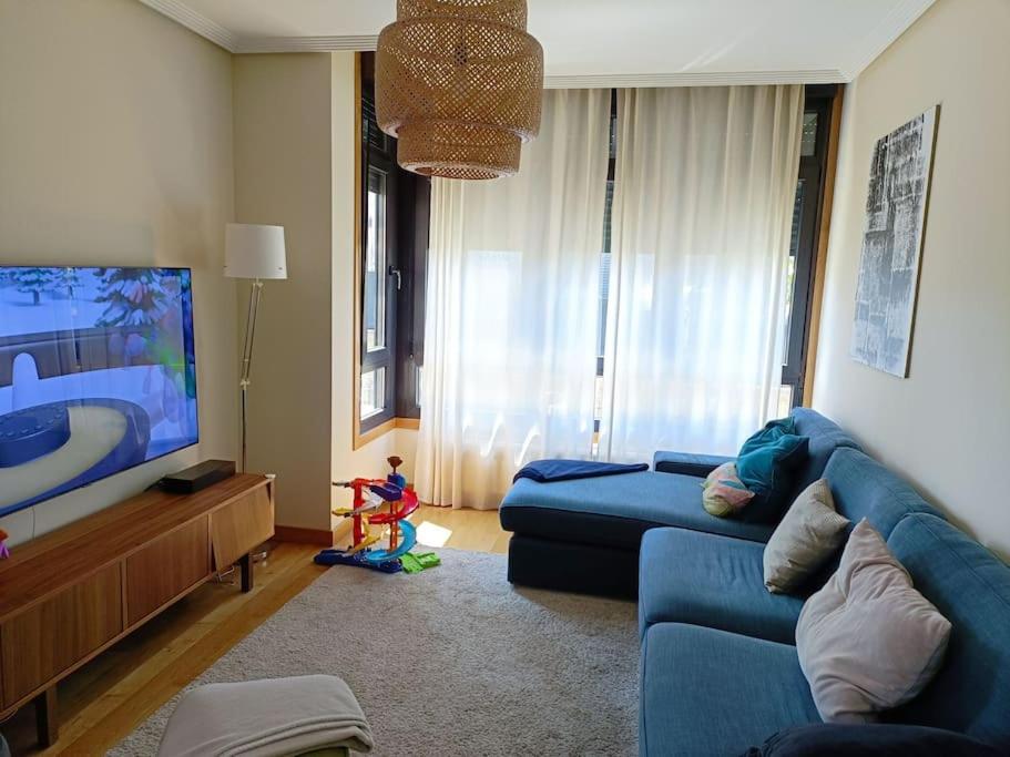 sala de estar con sofá azul y TV en Casa en la ciudad. en Ourense