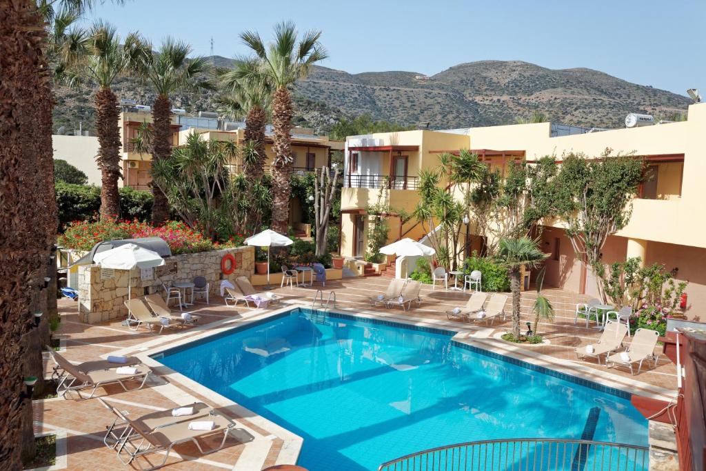 una piscina en un hotel con palmeras y un edificio en Latania Apartments, en Stalida