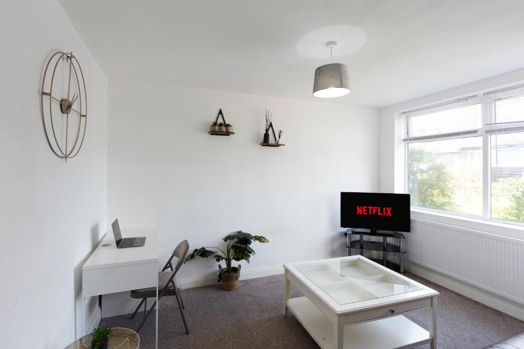 uma sala de estar branca com uma secretária e uma televisão em Spacious home close to city centre location em Leeds