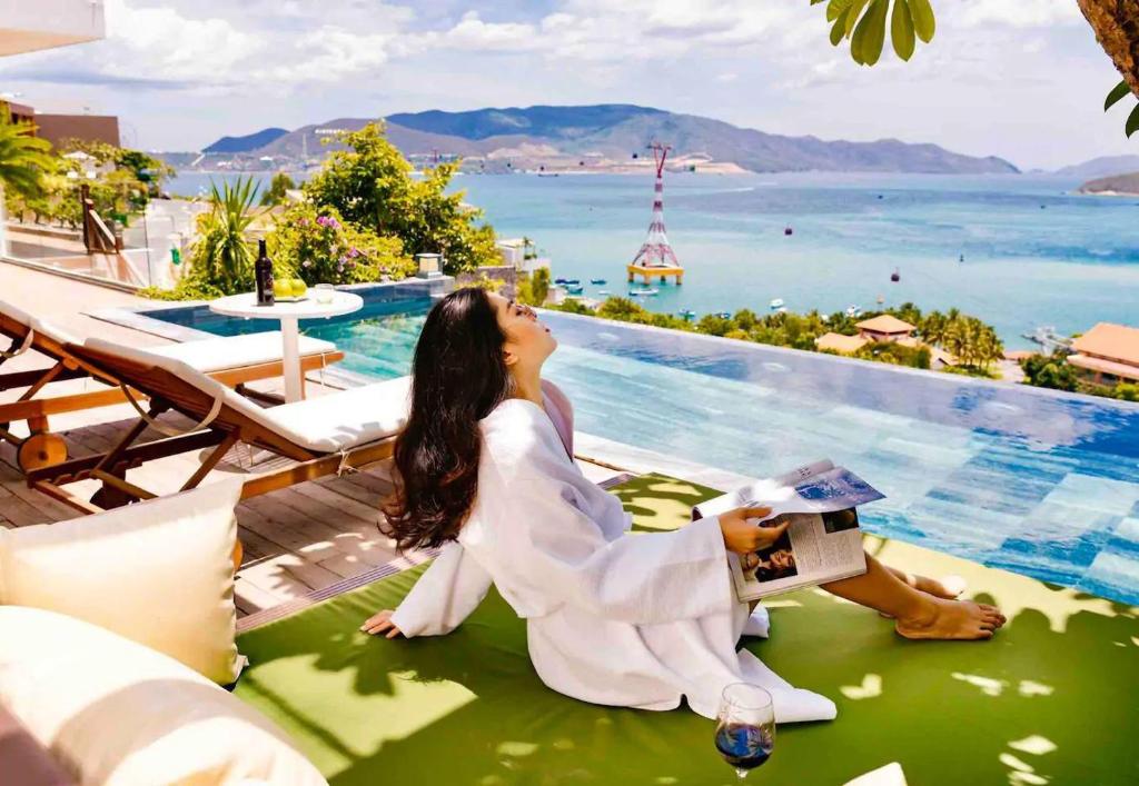 une femme assise sur une couverture à côté d'une piscine dans l'établissement The Hill Ocean Villa With 5 bedrooms and Infinity Pool, à Nha Trang