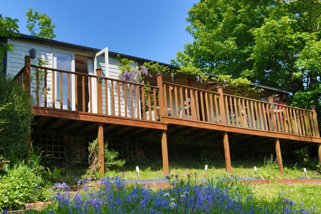 a deck on a house with people on it at Treetops Lodge, Bantham, South Devon, a tranquil rural retreat in Aveton Gifford